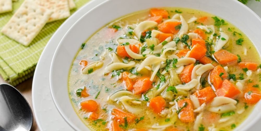 a bowl of homemade chicken noodle soup with fresh herbs